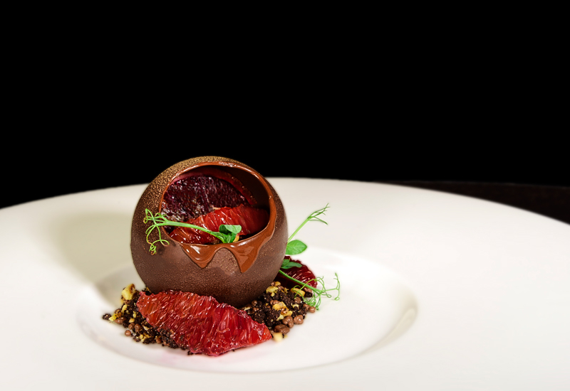 The signature dessert comprises a chocolate mousse dome, along with a scoop of blood orange and gianduja ice cream The signature dessert comprises a chocolate mousse dome, along with a scoop of blood orange and gianduja ice cream